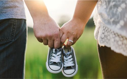 Jong koppel dat hand in hand baby sneakers vasthoudt